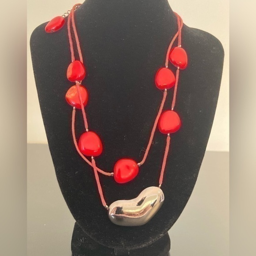 Red and golden necklace with beads and heart. Some beads have marks on one side.
